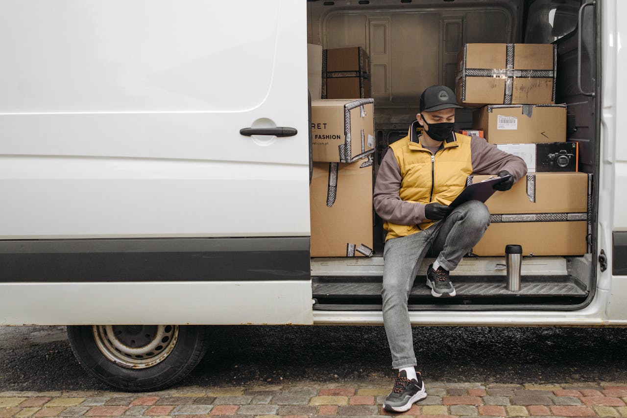 Courier organizing packages and making notes while sitting in a delivery van.